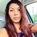 A woman with long red hair sitting in the back of a car.