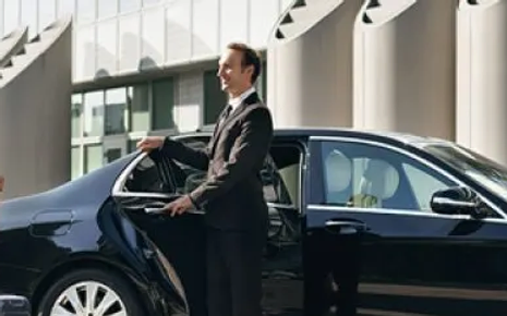 A man in a suit and tie standing next to a car.