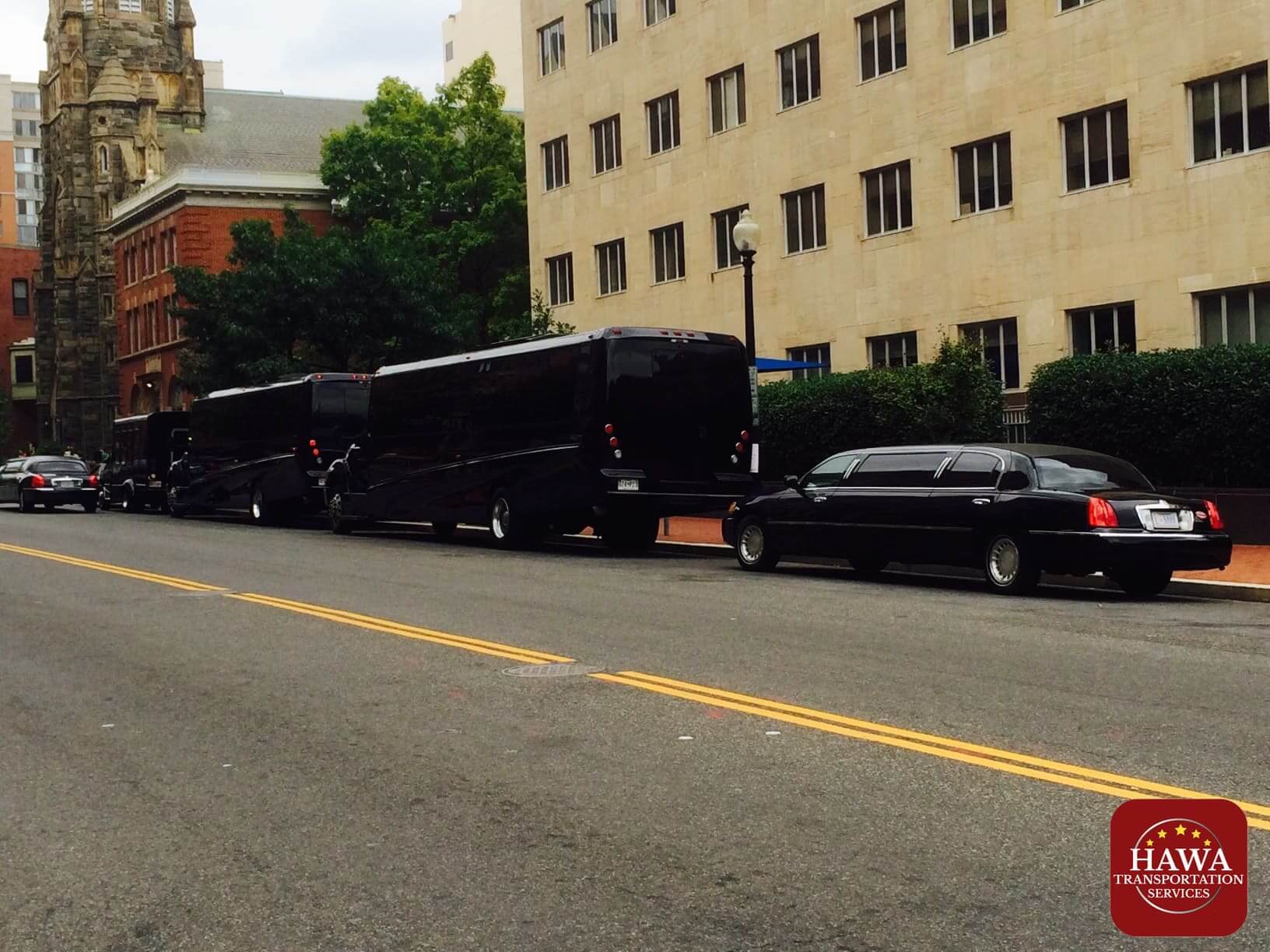 A black limo and a black car parked on the side of the road.