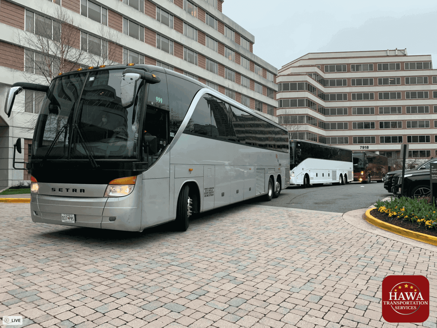 A silver bus is parked in front of some buildings